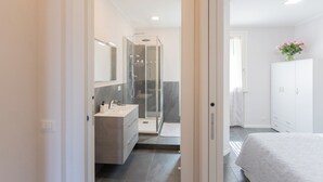 A modern bathroom with a glass shower enclosure, a vanity with a mirror, and a white cabinet. - Sant'Agostino Apartments by Rent all Como (Como)