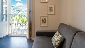 A room with a grey sofa, a door leading to a balcony with a metal railing, and three framed pictures on the wall. - Sant'Agostino Apartments by Rent all Como (Como)