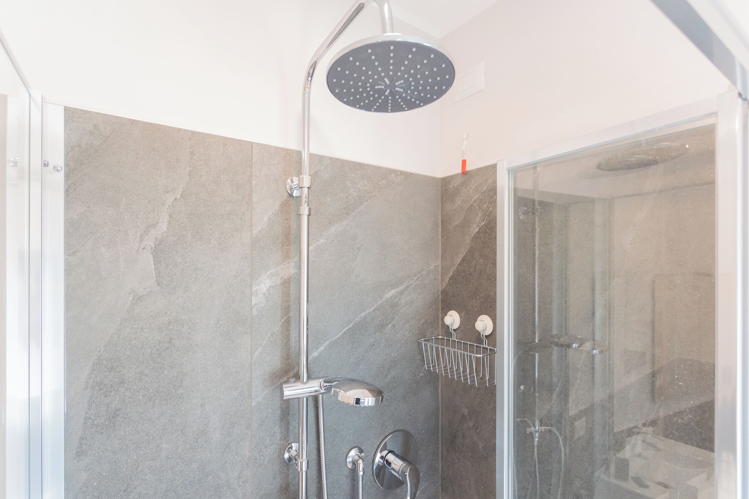 A modern shower with a handheld showerhead and a wall-mounted rain showerhead.