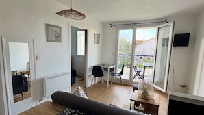 A modern living room with a sofa, a dining table, and a small kitchen area. - Apartment in residence with swimming pool, near Pontaillac page and casino (Vaux-sur-Mer)