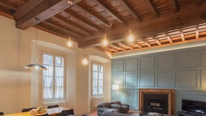 Amplia sala de estar con techo de madera alto, chimenea y comedor con mesa y sillas.