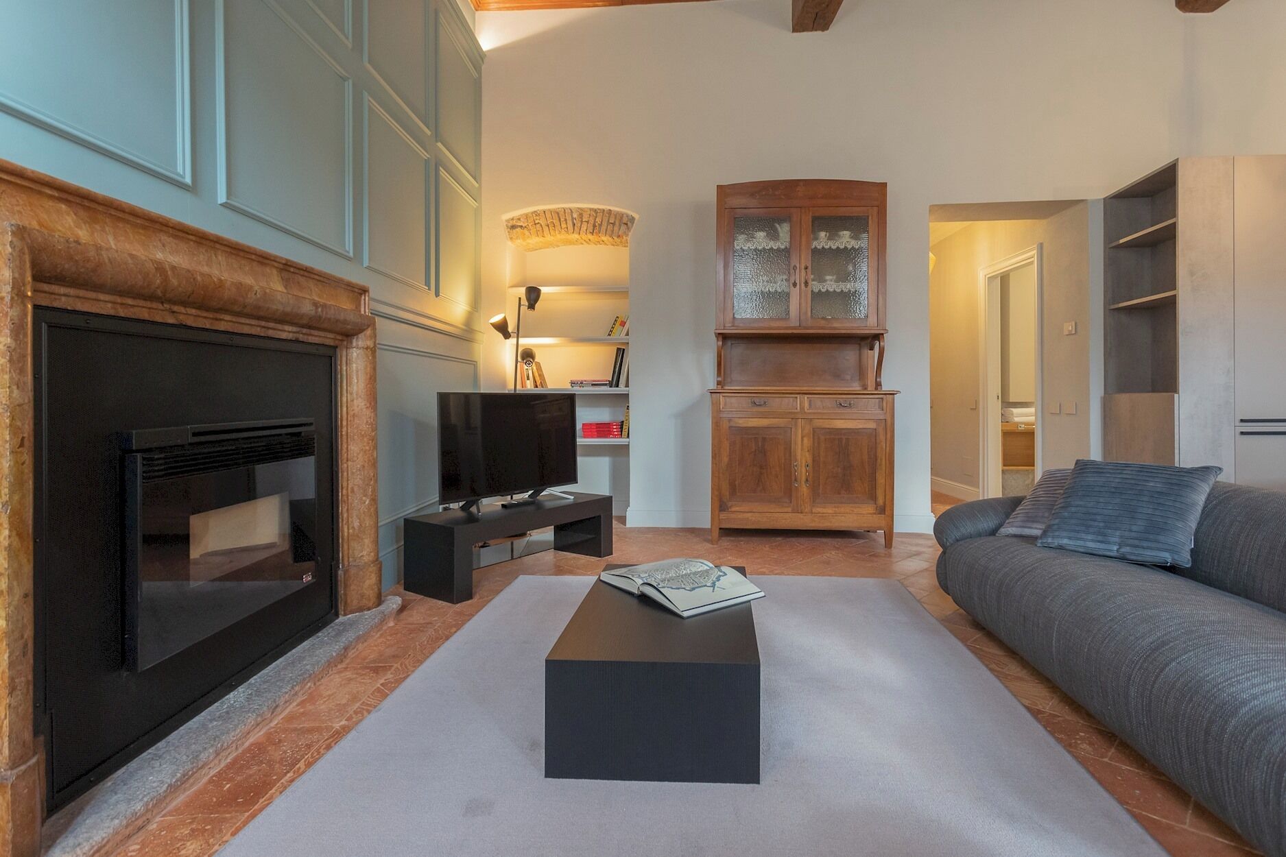 Una sala de estar con chimenea, televisor, sofá y un mueble.
