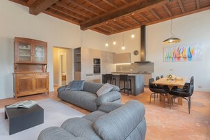 Una sala de estar moderna con un sofá seccional gris, un aparador de madera y un comedor con mesa y sillas de madera.