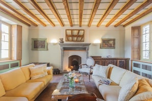 Una sala de estar acogedora con chimenea, dos sofás, una mesa de centro y un espejo.