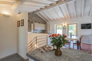 Una cocina con pared de piedra, vigas de madera en el techo y un comedor con mesa y sillas.