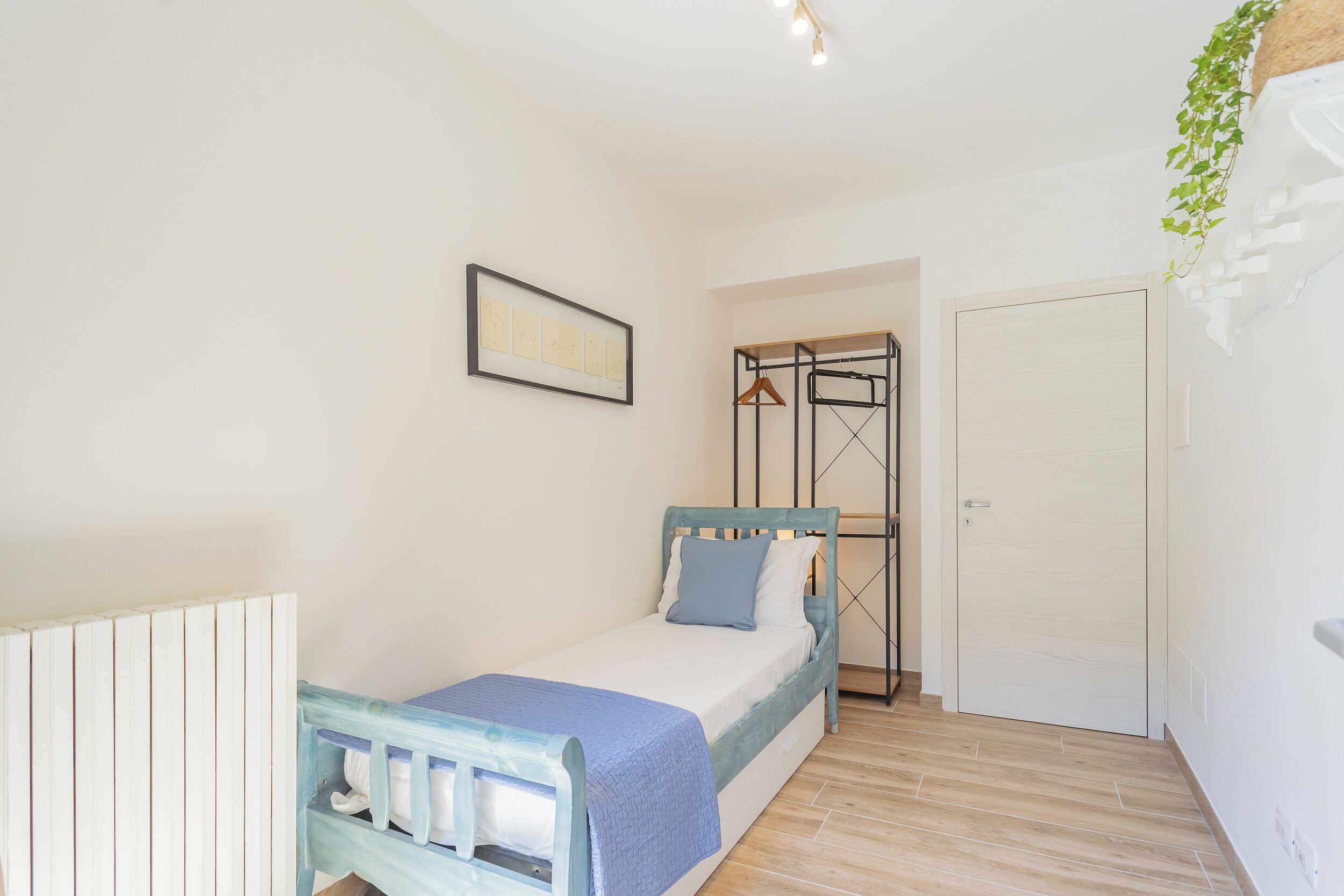 A bedroom with a bed, a wardrobe, a radiator, and a door.
