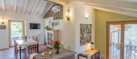 Une cuisine spacieuse avec un coin repas, un mur décoratif en pierre et une vue sur le balcon extérieur.