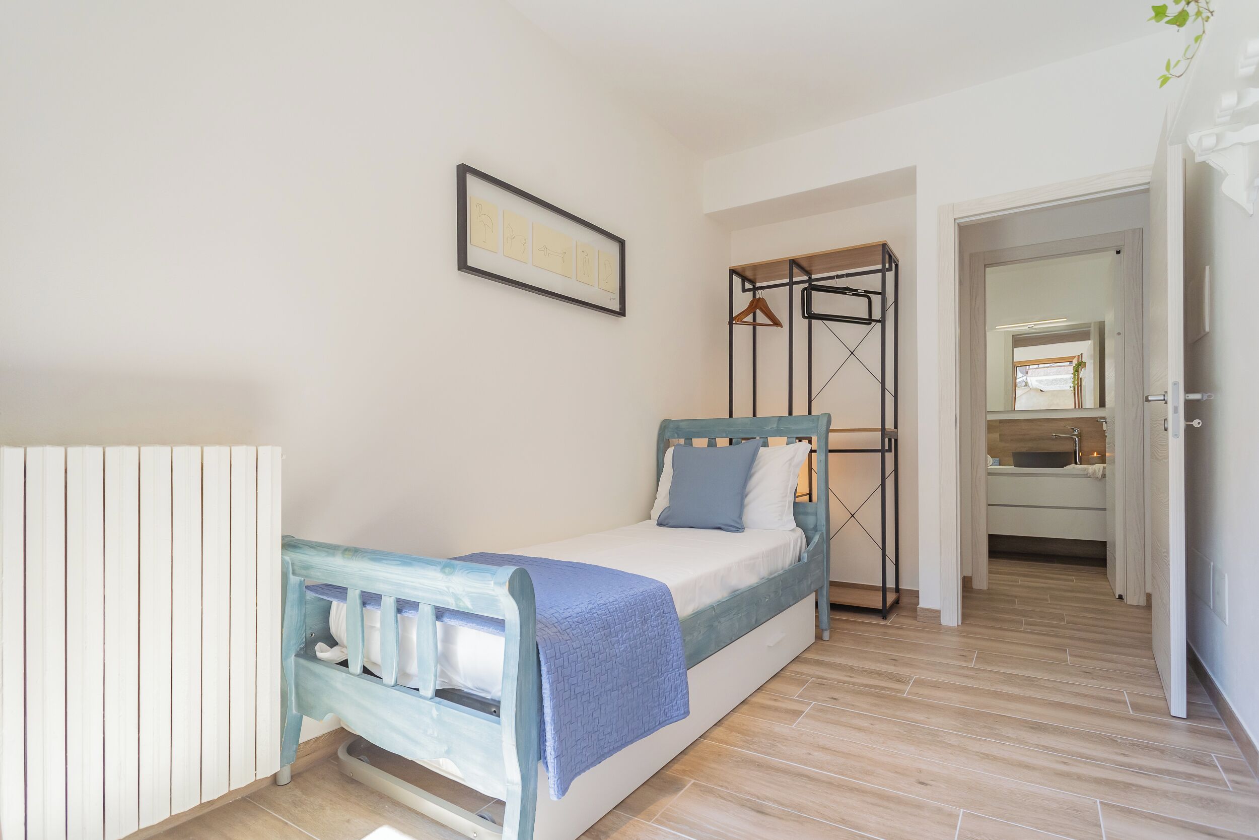 Ein Schlafzimmer mit Bett, Nachttisch, Kleiderschrank und einem durchgegangenen Tür sichtbaren Badezimmer.