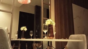 A dining area with a long table, two chairs, a vase with flowers, and two pendant lights. - Sweet Escape 7P at One Regis (Bacolod)