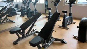 A gym with exercise equipment, large windows, and a mirror wall. - Sweet Escape 7P at One Regis (Bacolod)