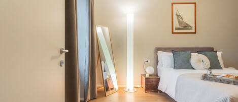 A bedroom with a bed, bedside table, and a mirror.