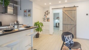 A modern kitchen with a central island, white cabinetry, and a sliding barn-style door leading to another room. - We Lake Como by Rent all Como (Argegno)