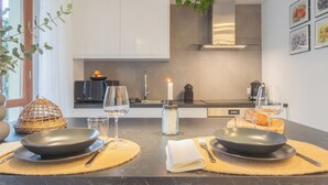 A modern kitchen with a dining area set for two, featuring a candle, wine glasses, and a basket. - We Lake Como by Rent all Como (Argegno)