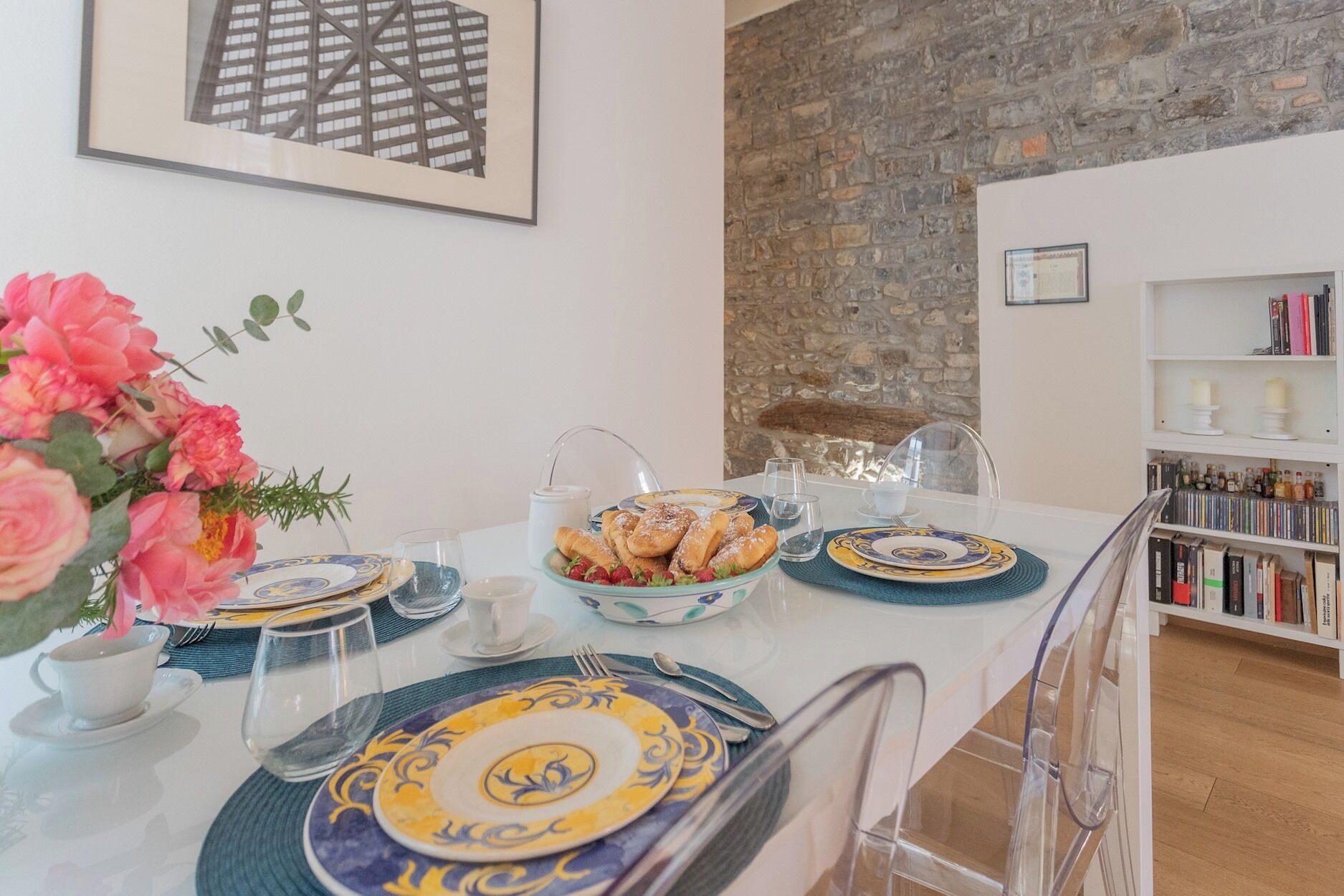 A dining table set with plates, glasses, and a bouquet of flowers.