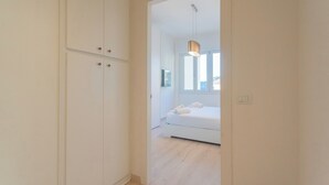 A hallway leading to a bedroom with a bed, a hanging light fixture, and a window. - White Lake View Apartment by Rent all Como (Como)