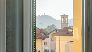 A view through an open window of a building with a bell tower, a satellite dish, and a hill in the background. - Zezio 44 by Rent all Como (Como)