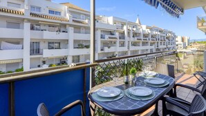 A balcony with a table set for dining, overlooking a row of white buildings with balconies. - BLAUMARINA 225 Roses (Rosas / Roses)