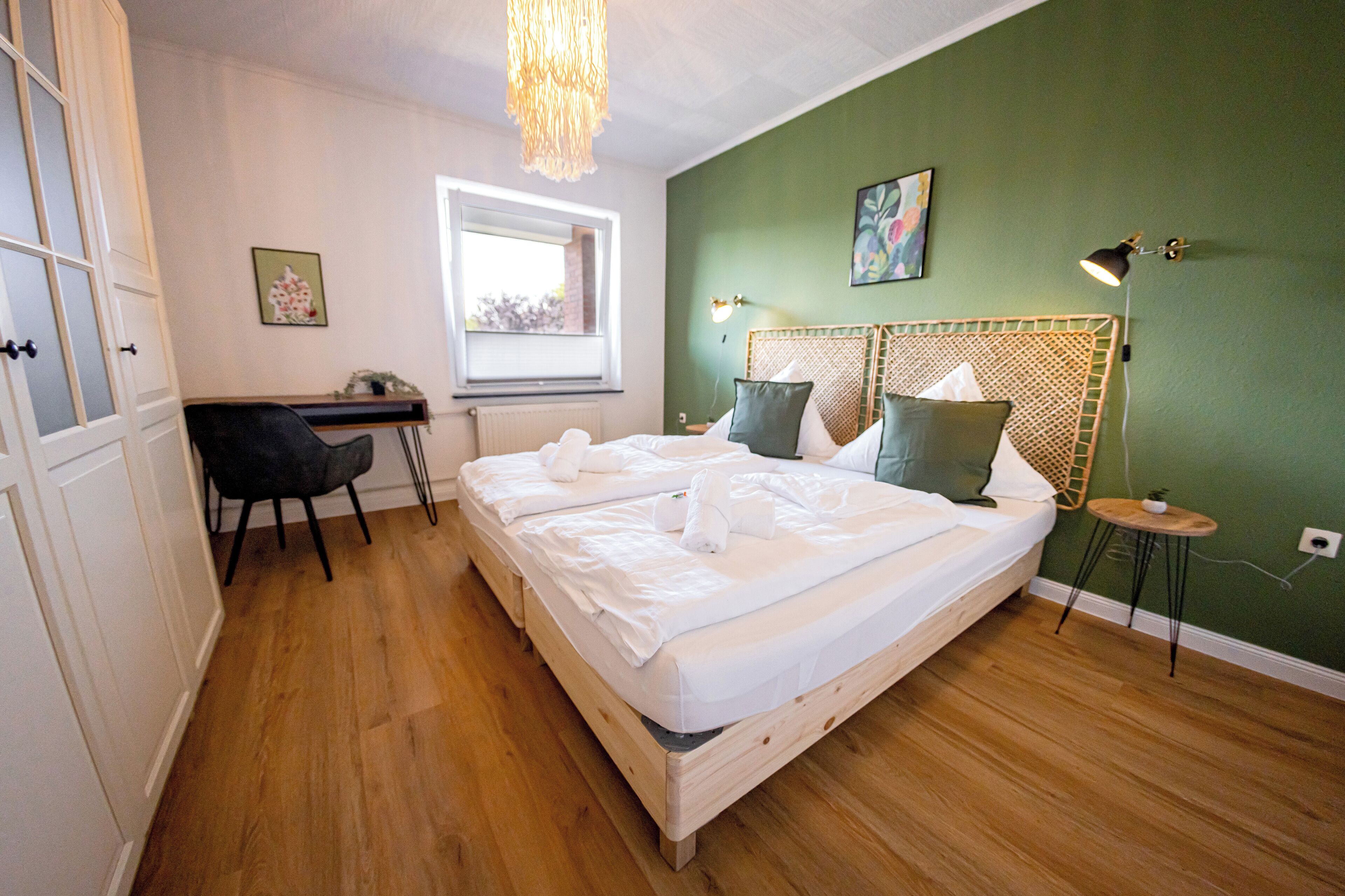 Een slaapkamer met een bed, bureau, stoel, raam en lamp.