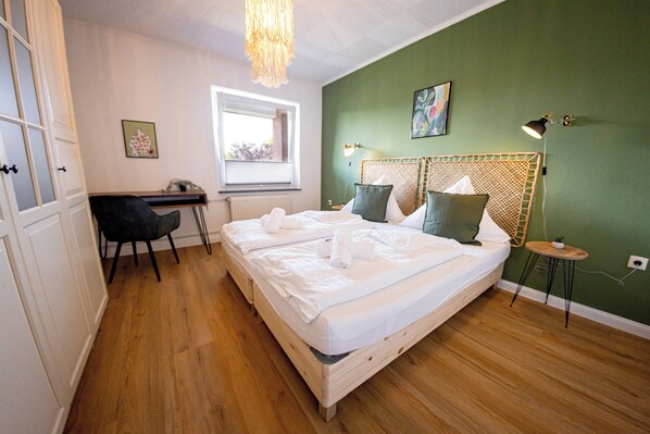 A bedroom with a bed, a desk, a chair, a window, and a lamp.
