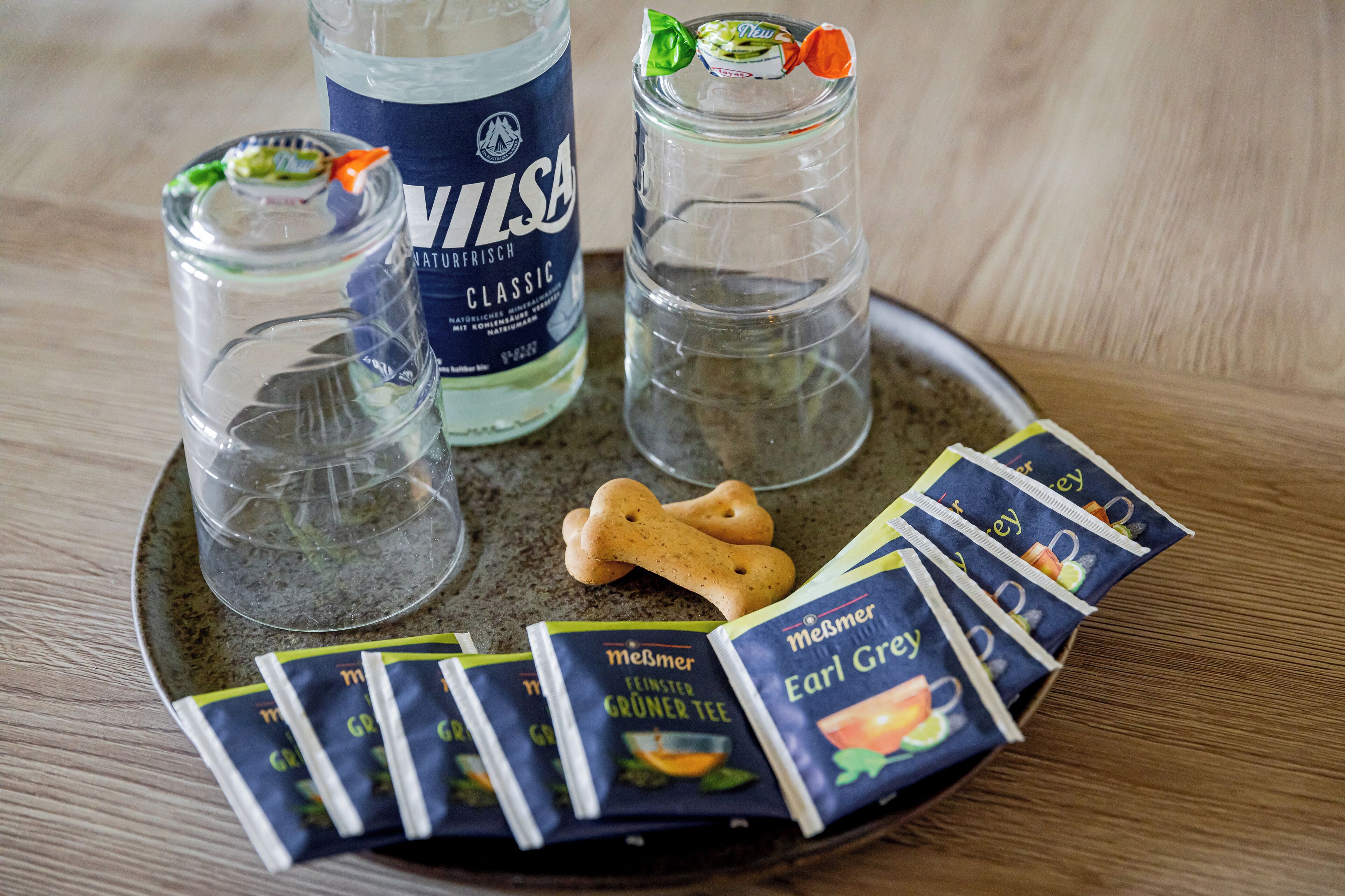 A tray with two shot glasses, a bottle, and packets of Earl Grey tea.