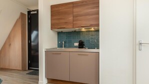 Eine kleine Küche mit Holzschränken, einer gefliesten Spritzschutzleiste und einer schwarzen Kaffeemaschine.