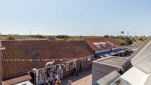 Eine Dachterrasse mit Ziegeldach, einem kleinen Geschäft und blauem Himmel.