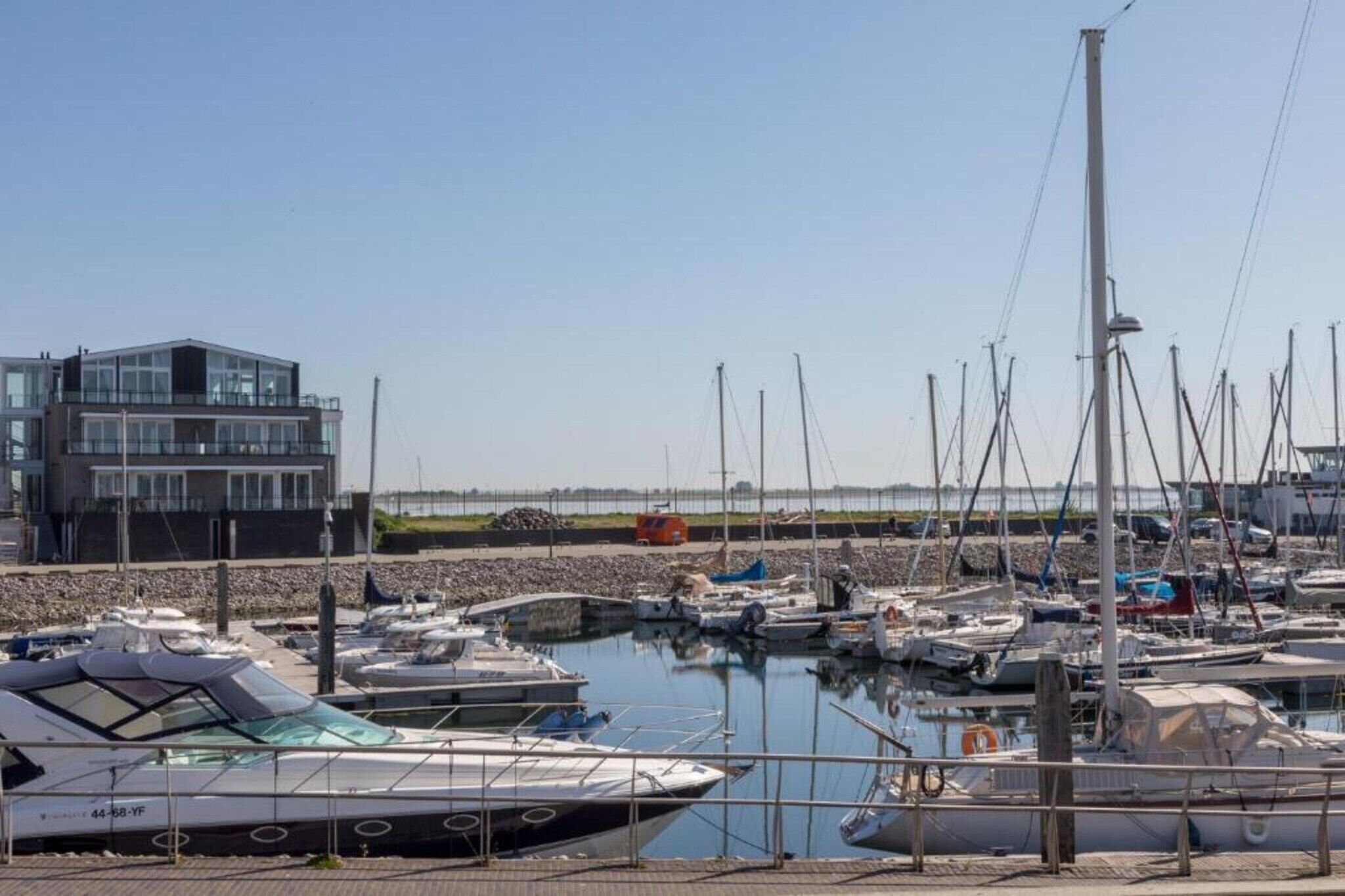Een jachthaven met meerdere boten afgemeerd, een modern gebouw en een heldere lucht.