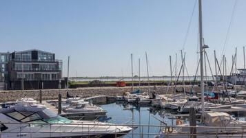Een jachthaven met meerdere boten afgemeerd, een modern gebouw en een heldere lucht.