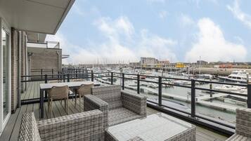 Een balkon met rieten meubilair met uitzicht op een jachthaven met boten.