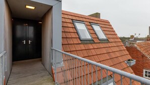 A modern building with a wooden roof, two skylights, and a wooden deck leading to a dark-colored door. - Cozy Couple’s Escape (Zoutelande)