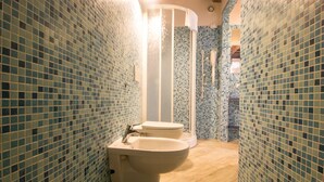A bathroom with blue mosaic tiles, a white sink, and a shower area. - Macine, one-bedroom terraced house (on two floors) (CECINA)