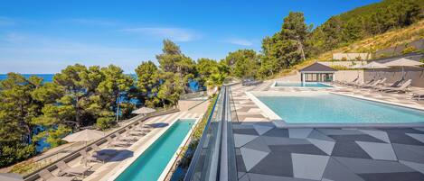 A rooftop pool with lounge chairs and a view of the sea.
