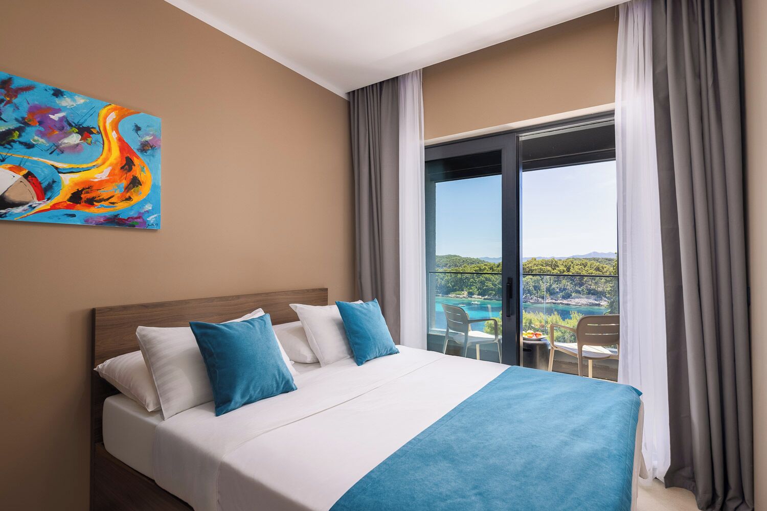 Habitación de hotel con cama, un cuadro en la pared y un balcón con vistas.