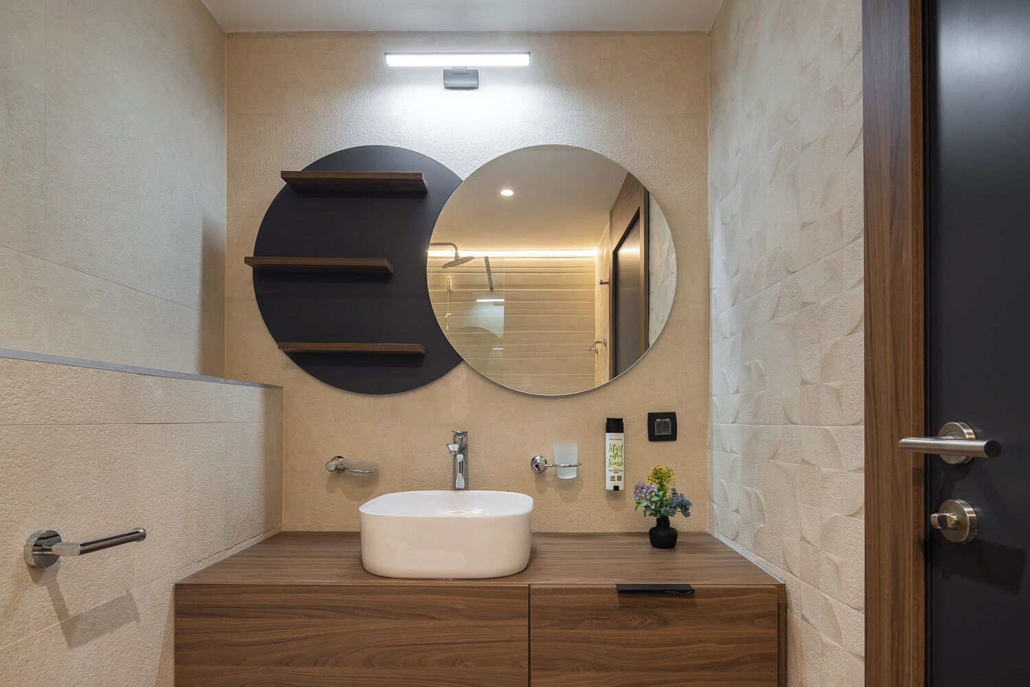 A modern bathroom with a wooden vanity, a round mirror, and a white sink.