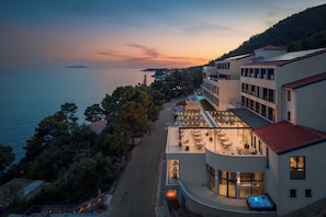 A hotel with a rooftop terrace overlooking a body of water, a pool, and a landscaped garden. - Aminess Alfir Hotel (Blato)