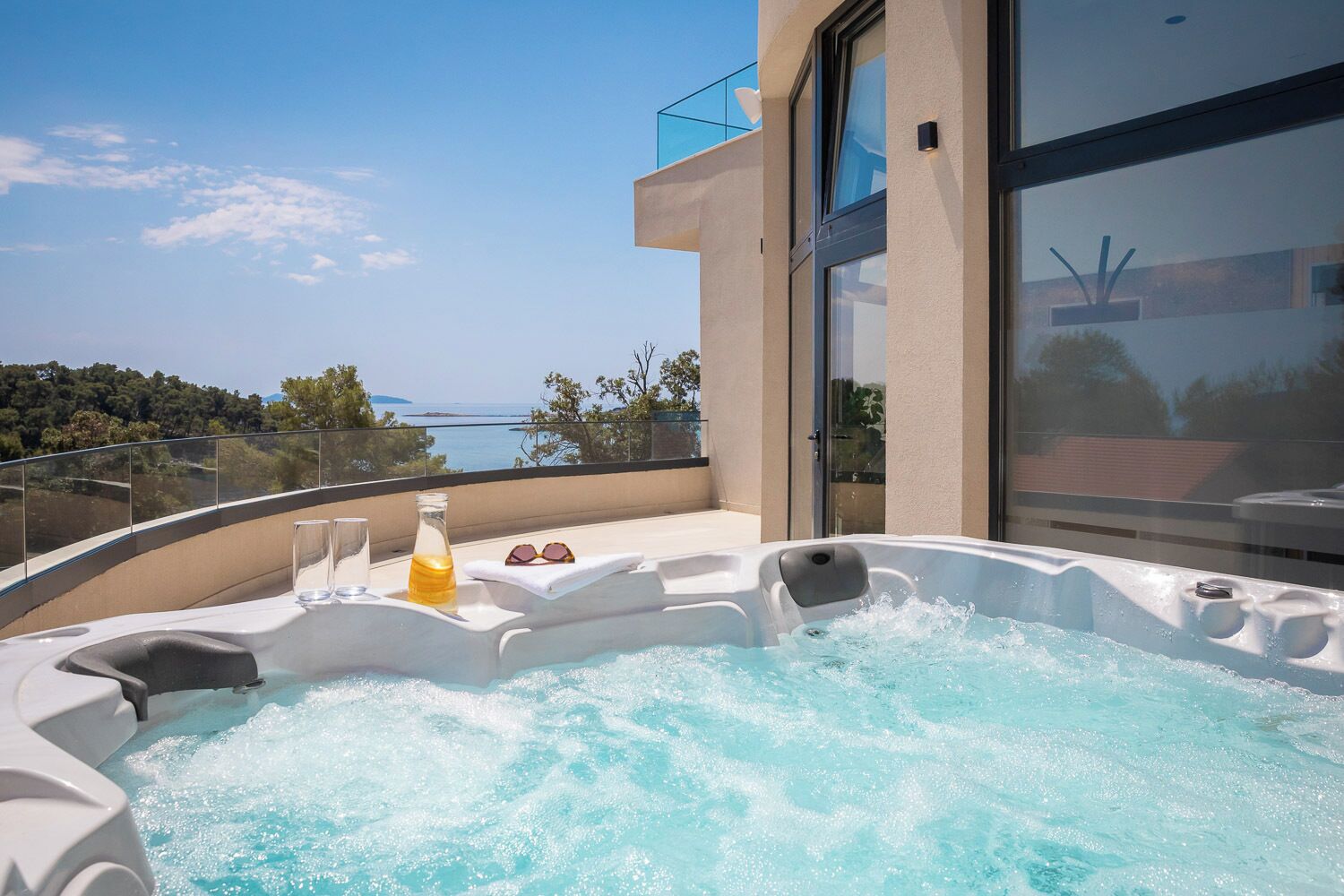 Un jacuzzi en un balcón con vistas despejadas al mar.