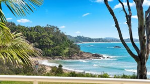 Vista costera con playa, costa rocosa y abundante vegetación.
