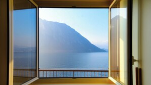 A window with a view of a calm sea and a mountain.