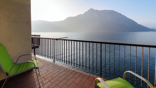 A balcony with a view of a calm sea and distant mountains.