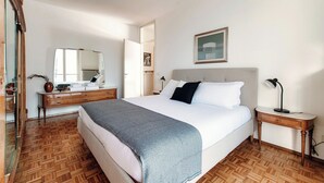 A bedroom with a large bed, a bedside table, a mirror, and a dresser.