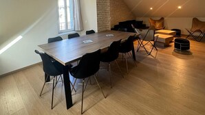 A spacious room with a large wooden table and black chairs, a stone wall, and a sloped ceiling with recessed lighting. - Residence VillaBelleFleur-Apartment L'Edelweiss (Château-Ville-Vieille)