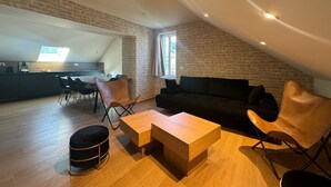 A modern loft apartment with exposed brick walls, a dining area, and a cozy seating area with a sofa and chairs. - Residence VillaBelleFleur-Apartment L'Edelweiss (Château-Ville-Vieille)