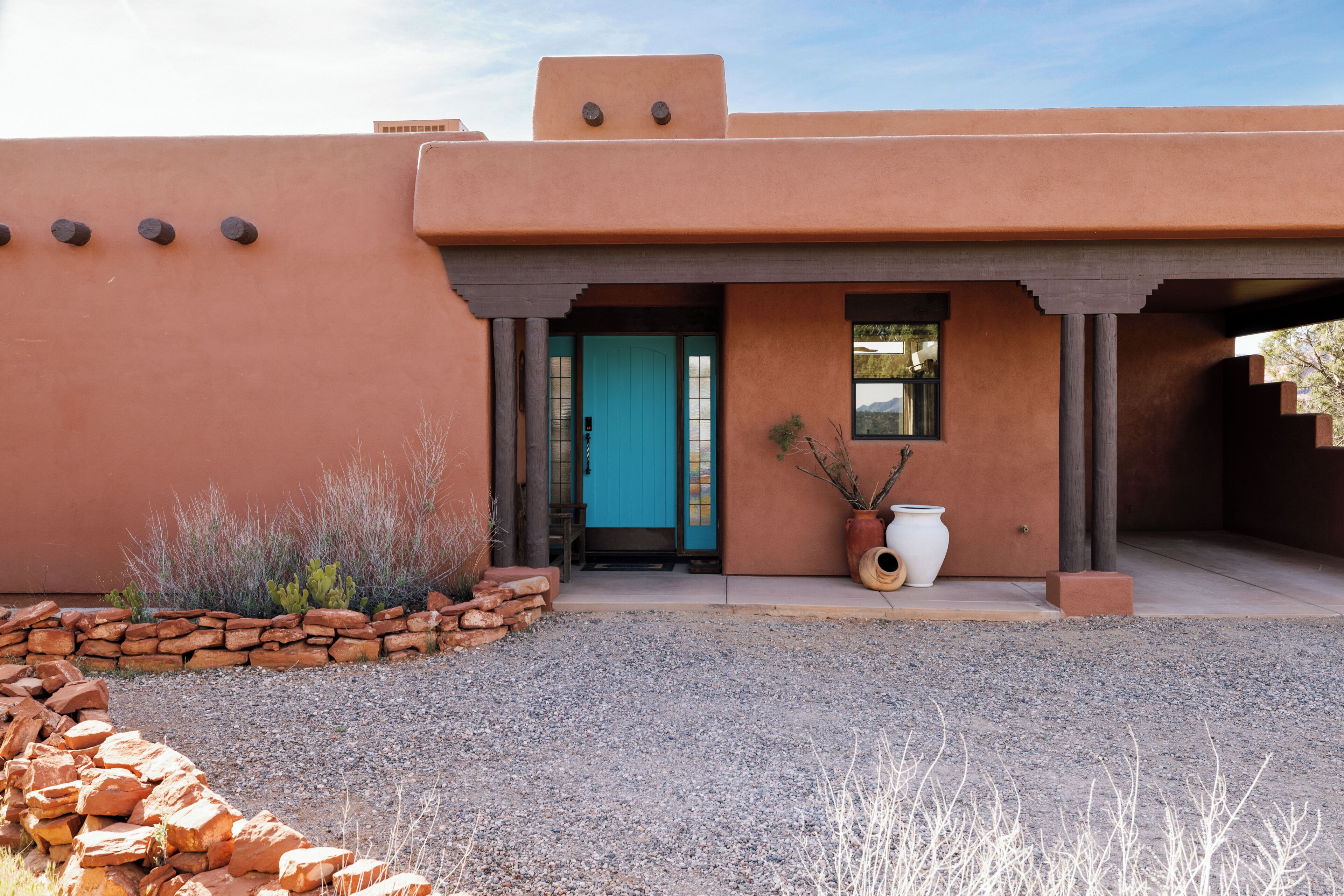 A building with a distinctive architectural style, featuring a flat roof, stucco walls, and a prominent entrance with a blue door.