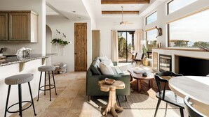 A spacious living area with a sofa, wooden beams, a dining table, and a kitchen area with bar stools.