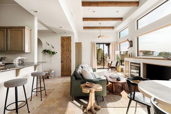 A spacious living area with a sofa, wooden beams, a dining table, and a kitchen area with bar stools. - Sedona's Best Villa - Best Views, Sunsets, Pool (Sedona)