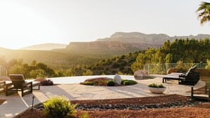 An outdoor patio with lounge chairs, a stone pathway, and a view of a mountainous landscape.