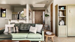 A modern living room with a green sofa, a wooden coffee table, and a cabinet with decorative items.