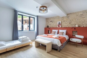 Une chambre à coucher moderne avec un grand lit, un banc, une chaise et une vue sur l’extérieur.