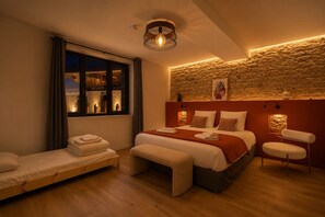 Una habitación de hotel con una cama grande, una cama más pequeña, un sofá, una silla y una ventana con vistas a edificios.