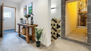 A hallway with a wooden bench, potted plants, and a wall with hexagonal tiles. - Renovated, spacious and comfortable 26-bed mill (Saint-Ignat)